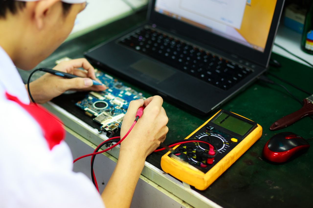 The Art of Drawing Readers In: Your attractive post title goes here Technician working on a laptop with multimeter in a professional workspace.